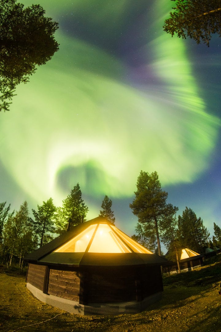 Crazy northern lights over aurora cottages at Aurora Village hotel Ivalo Lapland Finland.