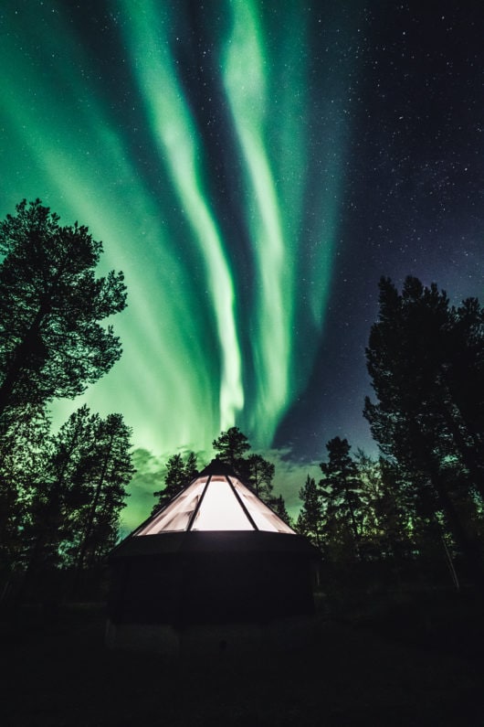 Magical northern lights over aurora cabin cottage at Aurora Village Ivalo Lapland Finland.