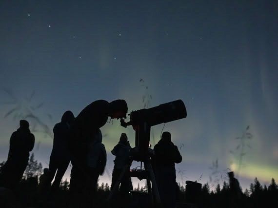 Guests using a telescope beneath the November night sky during Arctic Stargazing on 1 November 2024