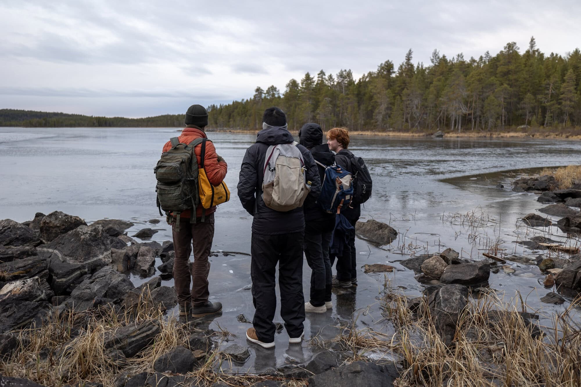 Guests hiking beside an unfrozen lake in Ivalo on 15 November 2024